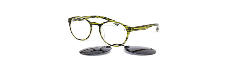 Clip-on Sunglass Lenses laying in front of a stylish pair of prescription glasses.
